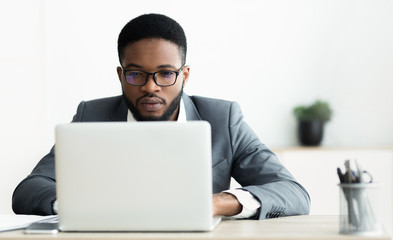 Concentrated african american guy working on laptop in office