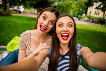 Wall Mural - Close up photo of cheerful schoolgirls with red lips brunette hair screaming making photo wearing striped t-shirt having bag backpack rucksack in city center