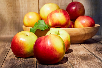 Fresh red apples with green leaves on a wooden old table. On a wooden background. Free space for text. soft focus