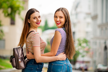 Wall Mural - Back side photo of charming youth hugging with tooth smile wearing striped t-shirt denim jeans in city outdoors