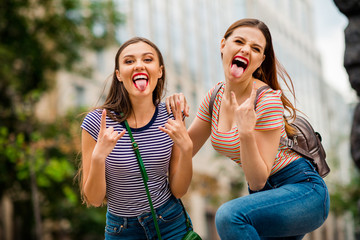 Wall Mural - Portrait of cool youth with red brunette hair pomade fooling showing rocker symbol wearing striped t-shirt denim jeans bag backpack handbag in town