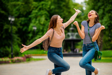 Poster - Portrait of delighted youth with red lips stick closing eyes raising palms fists wearing striped t-shirt denim jeans rucksack in town