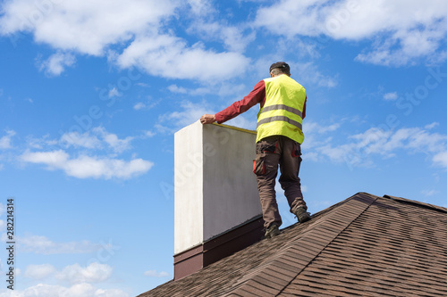 Cuadros en Lienzo Man measuring chimney on roof top of new house under construction