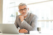 © goodluz - Mature businessman sitting at desk looking at camera