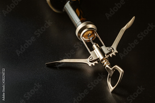 Fotomural Bottle of wine and corkscrew over dark background
