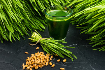 Green organic wheat grass drink over dark wood background,top view ,young grass stage.