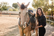© Liubov Levytska - Girl prepare her horse for ride on racetrack. Cheerful female jockey fasten saddle, grooming cute animal and smiling joyfully camera, enjoy fresh air, taking care rancho, farm pets