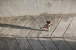 © Liubov Levytska - Overhead view athletic female jogger running on concrete track in black sportsbra and shrots, move towards morning sun during daily outdoor workout, fitness jogging prepare to marathon competition