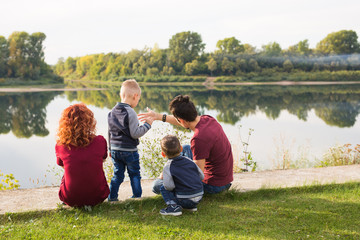 Children, parenthood and nature concept - Big family sitting on the grass