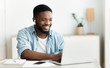 Leinwandbild Motiv Smiling african-american guy in earphones studying foreign language online