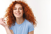 Tenderness, Beauty, Haircare Concept. Alluring Sensual Young Woman With Natural Curly Red Hair, Rolling Strand On Finger Silly, Smiling Toothy Looking Happy And Coquettish, Standing White Background