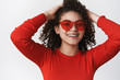 © Cookie Studio - Close-up relaxed joyful good-looking woman curly-haired enjoy weekend vacation look happily smilling toorhy hold hands behind head lazy wearing red trendy sunglasses, standing white background