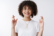 © Cookie Studio - Woman hope win praying. Attractive hopeful curly-haired girl student cross fingers good luck shut eyes prepare hear results dream come true making wish standing faithfully awaiting, white background