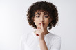 © Cookie Studio - Close-up girl curly hair stylish asking keep quiet say shh hiding secret seal lips promise, hold index finger pressed mouth shush gesture tell gossip confidential information, white background