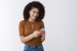© Cookie Studio - Happy carefree stylish attractive 20s girl holding smartphone laughing funny message look phone display writing lol answer friends social media page use cool new app standing white background