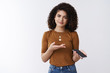 © Cookie Studio - What was message about. Confused clueless pretty modern 20s curly dark hair girl hold smartphone pointing phone shrugging clueless raise eyebrow curious puzzled receive strange text white background