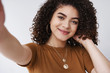 © Cookie Studio - Close-up modern stylish happy young pretty curly girl touch neck soft gentle smile exten arm hold camera taking selfie smartphone grinning express happiness joy photographing herself