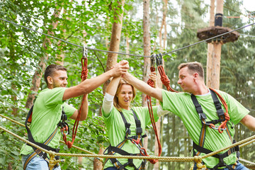 Young people in the high ropes course celebrate teamwork