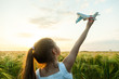 Child girl holding airplane toy during running in the field