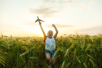 Wall Mural - Child girl holding airplane toy during running in the field