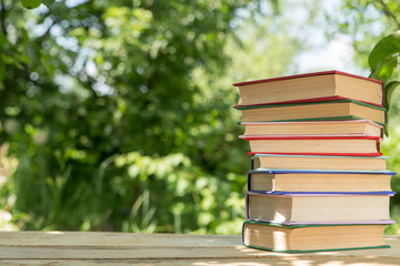 Books on a wooden table in a garden. Sunny summer day, reading in a vacation concept