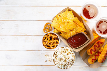 Selection of stadium game foods - nachos, pop corn, pretzels, corn dogs, rustic wood background