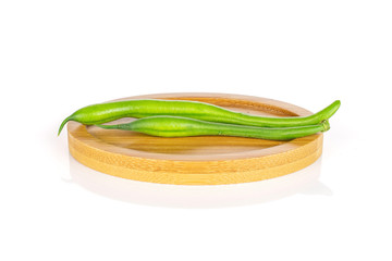 Group of two whole fresh green bean on oval bamboo coaster isolated on white background