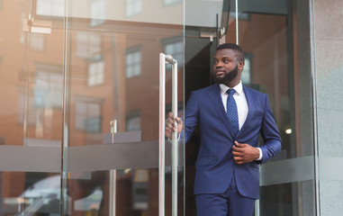 Wall Mural - Confident african businessman walking out of modern office center