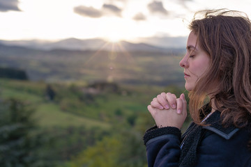 Christian worship and praise. A young woman is praying and worshiping in the evening.