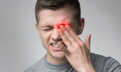 upset man suffering from strong eye pain