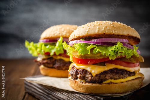 Fotografía Two homemade tasty burgers on wood table. Selective focus.