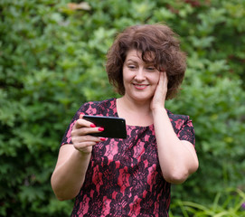 Wall Mural - Woman looks at the phone on phone screen in nature