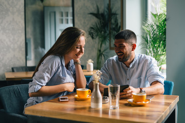 Wall Mural - A happy young couple on a date at a fancy restaurant looking at a menu on tablet