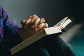 Man praying on holy bible in the morning.teenager boy hand with Bible praying,Christians and Bible study concept.copy space