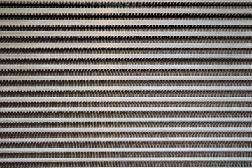 light grey surface of a latticed metal fence with jagged stripe elements