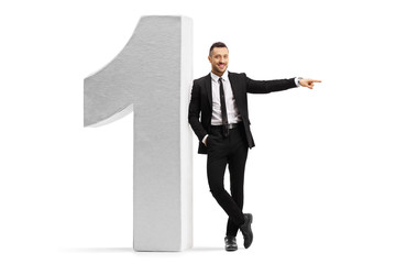 Wall Mural - Young businessman leaning on a large number one and pointing to the side