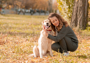 Wall Mural - Beautiful smiling woman with cute golden retriever dog