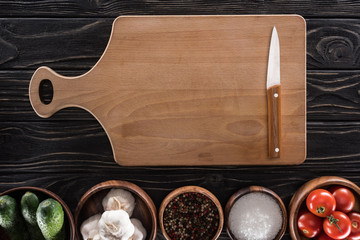 Wall Mural - top view of cutting board, cherry tomatoes, salt, garlics, cucumbers, knife and spices