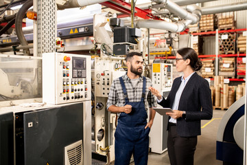 Two young business partners discussing working methods of industrial production