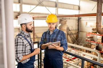 One of young contemporary engineers showing his colleague online information