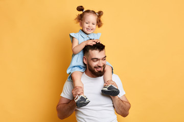 positive parent and his daughter express positive emotion during the game. close up photo. isolated yellow backgrround