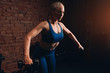 © the faces - slim muscular blonde woman doing exercises for abdorminal muscles at gym with loft interior, close up side view photo.