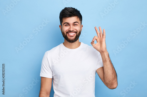 Fotografía positive attractive Arab young man showing ring gesture with fingers