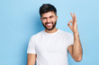 happy funny bearded man winking his eye and showing ok sign, isolated on blue background, everything is under control. joke , fun concept
