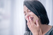 © LIGHTFIELD STUDIOS - selective focus of depressed brunette woman covering mouth and crying at home