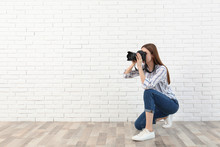 Professional Photographer Taking Picture Near White Brick Wall. Space For Text
