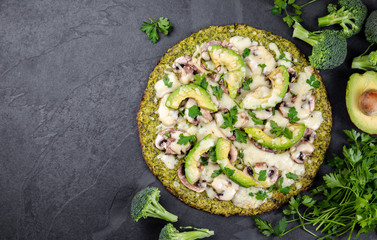 Green broccoli dough crust pizza with avocado, cheese. Low carbs, ketogenic diet vegan vegetarian pizza on slate background top view