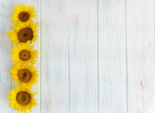Summer Bright Light Wooden Background With Flowers Of Sunflowers On The Sides. Frame For Text With Sunflowers. Greeting Card With Flowers View From The Top.