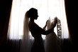 © Wedding photography - Bride holding white wedding dress with lace, embroidery. Bride getting ready