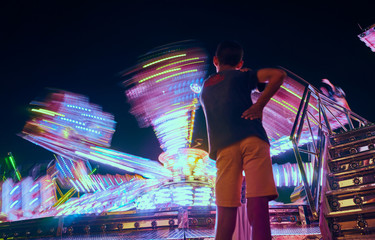 Children watching a fairground attraction at sunset. People enjoying the fairground attractions.